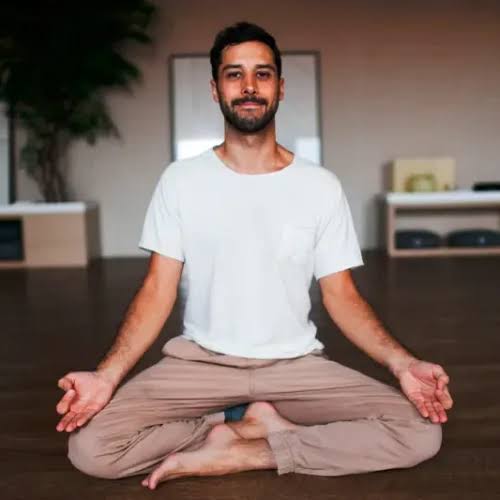 Caio Reis meditando sentado no chão de uma sala